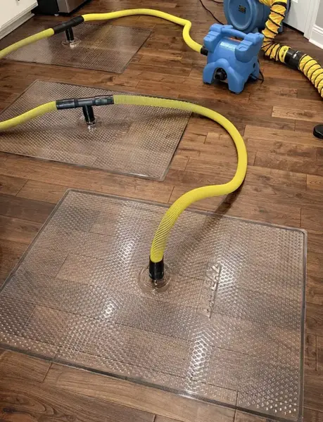 Floor drying mats connected to a blower on a wet wood floor in Woodland Hills