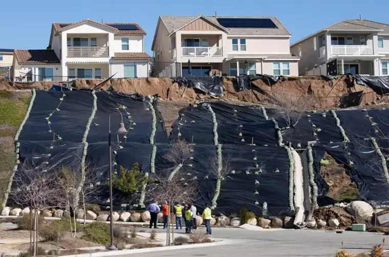Hillside slope covered with plastic sheeting below homes after a winter storm in the Los Angeles area