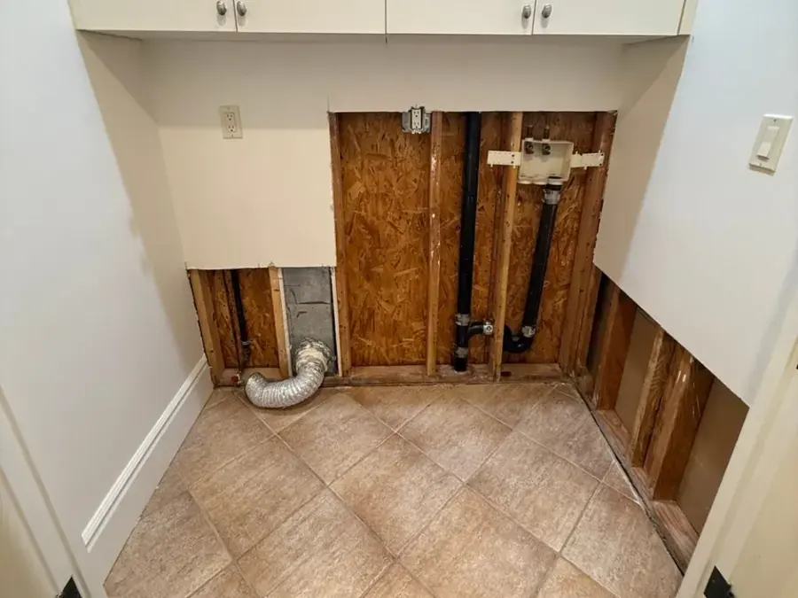 Laundry wall opened around the washer box to dry framing after a supply line leak in Woodland Hills