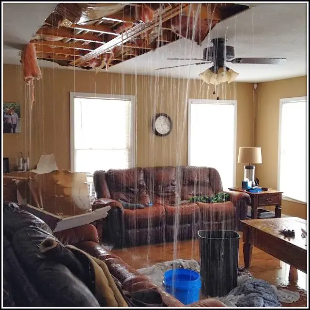 Rain water pouring through an opened living room ceiling from a roof leak